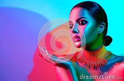 Fashion model woman in colorful bright lights with trendy makeup and manicure posing Stock Photo