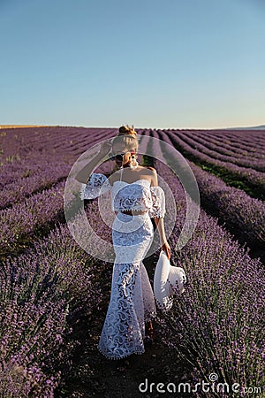Sexy woman with blond hair in elegant clothes with accessories posing in blooming lavender fields Stock Photo