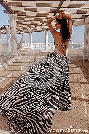 beautiful woman with dark hair in elegnt dress with zebra print posing in beach club Stock Photo