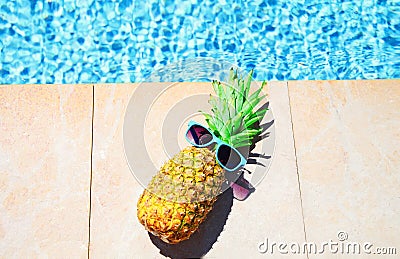 Fashion pineapple with sunglasses, blue water pool background, summer holidays, Stock Photo