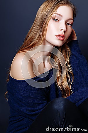 Fashion portrait of beautiful young woman with blond hair. Girl in a a blue pullover on a black background Stock Photo