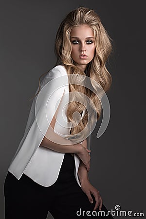 Fashion portrait of blonde woman dressed white jacket and black breeches Stock Photo