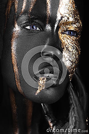 Fashion portrait of a dark-skinned girl with gold make-up. Beauty face. Stock Photo