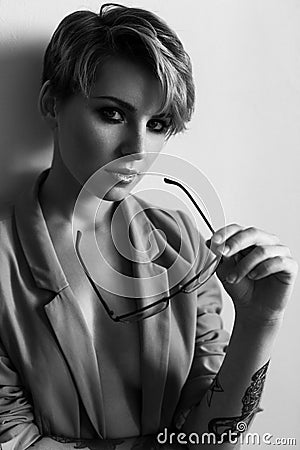 Fashion portrait of a girl with short hair wearing a jacket with glasses in ha Stock Photo