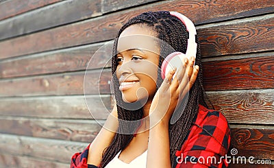 Fashion portrait happy smiling african woman with headphones is enjoying listens to music over background Stock Photo