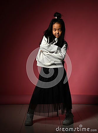 Fashion portrait of a little Korean model girl posing professionally on a red background. Stock Photo