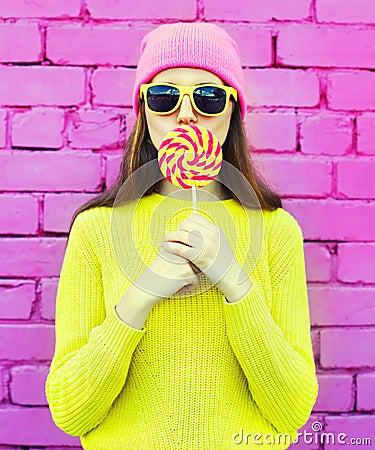 Fashion portrait pretty cool girl having fun with lollipop over pink Stock Photo