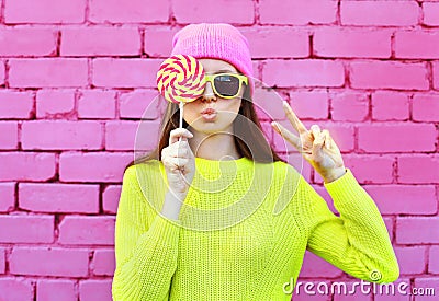 Fashion portrait pretty cool girl with lollipop having fun over colorful pink Stock Photo