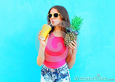 Fashion portrait pretty cool girl with pineapple drinking juice from cup over colorful Stock Photo