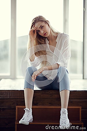 Fashion portrait of blonde woman. Jeans and sneakers. Stock Photo