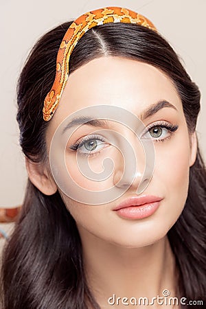 Fashion portrait of young brunette woman with snake on her head, symbol of youth, beauty, skin elasticity and anti Stock Photo