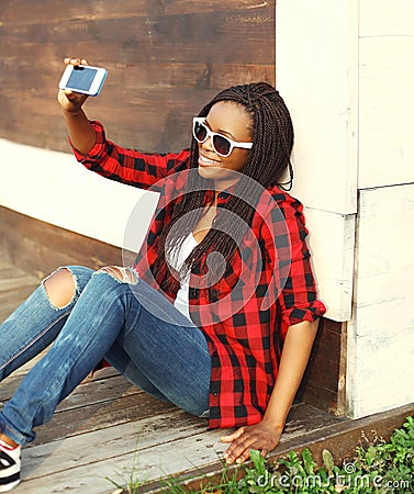 Fashion pretty smiling african woman makes self-portrait on smartphone Stock Photo