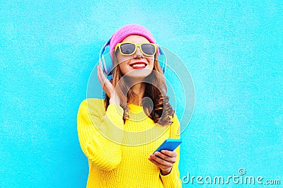 Fashion pretty sweet carefree girl listening to music in headphones with smartphone wearing colorful pink hat yellow sunglasses Stock Photo