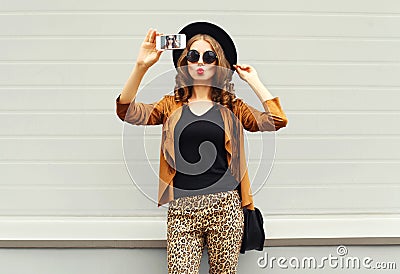 Fashion pretty young woman model taking photo picture self-portrait on smartphone wearing retro elegant hat, sunglasses Stock Photo