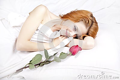 Fashion red-haired girl with rose in the bedroom. Stock Photo