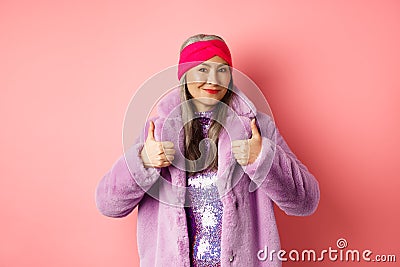 Fashion and shopping concept. Asian fashionable lady in winter coat showing thumbs-up, smiling and looking satisfied Stock Photo