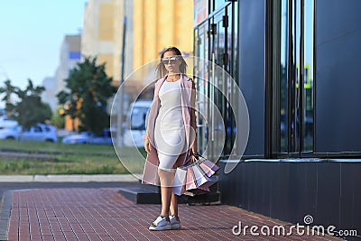 Fashion Shopping Girl Portrait. Beautiful girl in sunglasses. After day shopping. Girl with shopping bags. Shopper. Sales Stock Photo