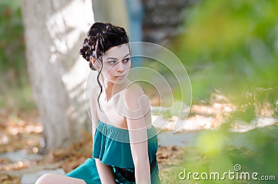 Fashion slim woman wearing green strapless short dress sitting sidewalk Stock Photo