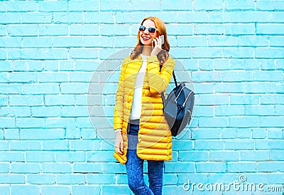 Fashion smiling woman talks on a smartphone on brick background Stock Photo