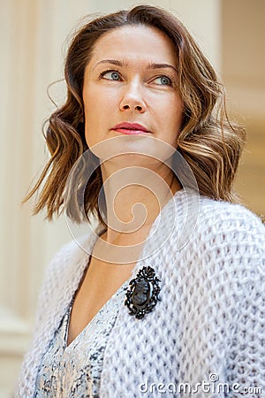 Beautiful middle-aged woman in gray knitted overcoat with black brooch Stock Photo