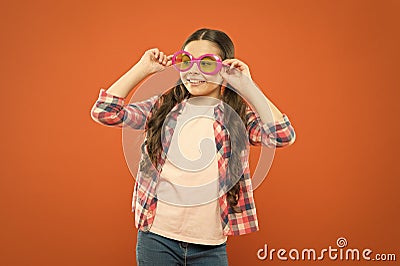 Fashion sunglasses keeping kids eyes protected and looking good. Small fashion model on orange background. Adorable Stock Photo