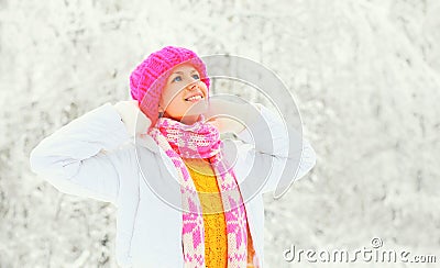 Fashion winter portrait happy woman wearing a colorful knitted hat sweater scarf over snowy background Stock Photo