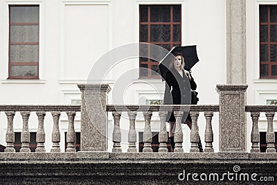 Fashion woman in black coat with umbrella at the balustade Stock Photo