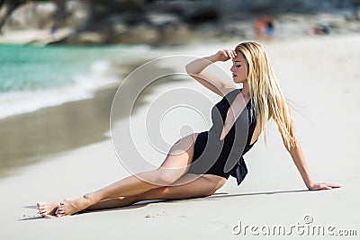 Fashion woman in black swimwear lying on tropical beach. Portrait of beautiful young woman lying on side enjoying sunbath near the Stock Photo