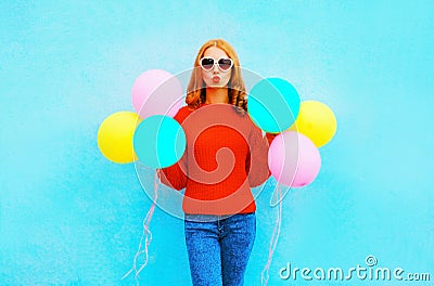 Fashion woman does an air kiss with colorful balloons on blue Stock Photo