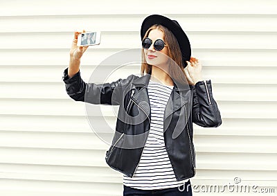 Fashion woman makes self portrait on smartphone in black rock style over white Stock Photo