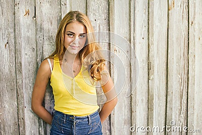 Fashion young blonde woman in yellow Tshirt over pale wooden background Stock Photo