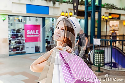 Fashion young girl portrait. Beauty Woman with craft paper bags in Shopping Mall. Shopper. Sales. Shopping Center. Space for text. Stock Photo