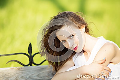 Fashionable blonde girl sitting on a bench in a city park Stock Photo