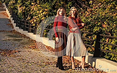 Fashionable clothes. Femininity and tenderness. Friends girls. Fall fashion. Pleated skirt fashion trend. Women walking Stock Photo