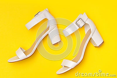 Fashionable concept. White shoes on yellow background, top view Stock Photo