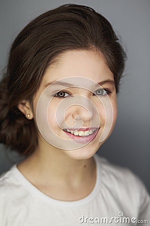 Fashionable cute european female with bun smiling broadly and glancing at camera while standing over white background Stock Photo