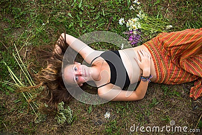 Fashionable cute girl lying on his back with her hair down on the grass. Stock Photo