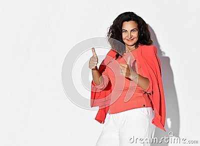 Fashionable elegant satisfied woman model with long curly hair in vibrant formal elegant suit showing approval thumbs-up gesture Stock Photo