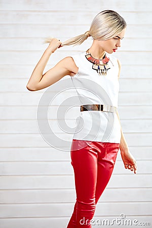 Fashionable girl standing in red leather pants and white top Stock Photo