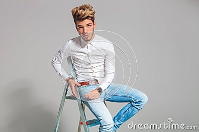 Fashionable hipster sitting on a ladder while posing Stock Photo