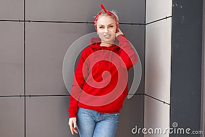 Fashionable joyful young woman with a cute smile in modern fashionable clothes with a red bandana is standing Stock Photo