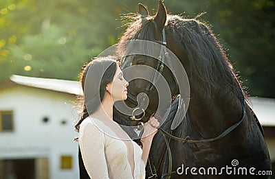 Fashionable lady with white bridal dress near brown horse. Beautiful young woman in a long dress posing with a friendly horse Stock Photo