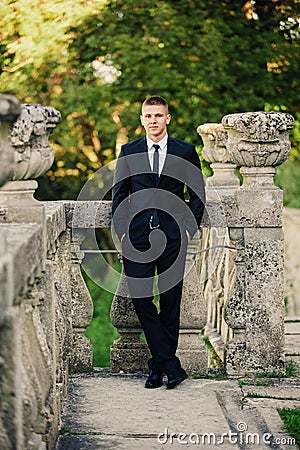 Fashionable model groom standing on the balcony leaning on railing Stock Photo