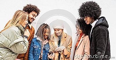 Fashionable multiethnic friends having fun together outdoors, looking at mobile phone Stock Photo