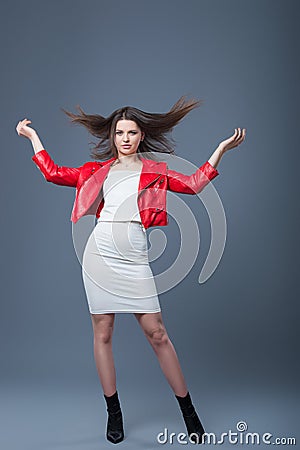 Fashionable style, fashion women`s clothing, color combination. Beautiful brunette girl in white dress and red leather jacket. Stock Photo