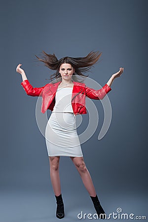 Fashionable style, fashion women`s clothing, color combination. Beautiful brunette girl in white dress and red leather jacket. Stock Photo