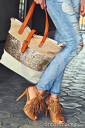 Fashionable woman wearing high heel sandals with fringe, jeans and bag. Stock Photo