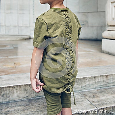 Fashionable young kid wearing green t-shirt and summer shorts. Kids street fashion summer clothes. Stock Photo