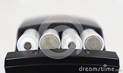 Fast charging of AA batteries. Rechargeable batteries in a black charger with four battery cells on a white background Stock Photo