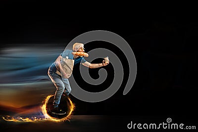 Fast delivery service - deliveryman on unicycle driving with order in fire on dark background Stock Photo